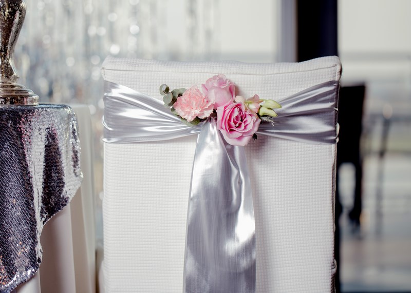 różowe kwiaty na ślub na krzesła dla pary młodej
